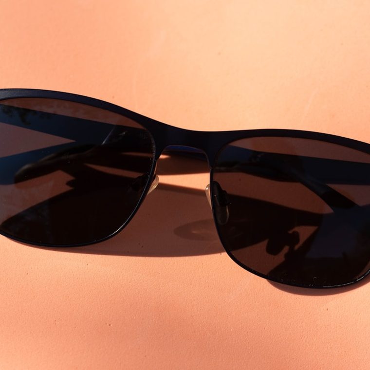Gafas de sol de pasta negra sobre fondo coral