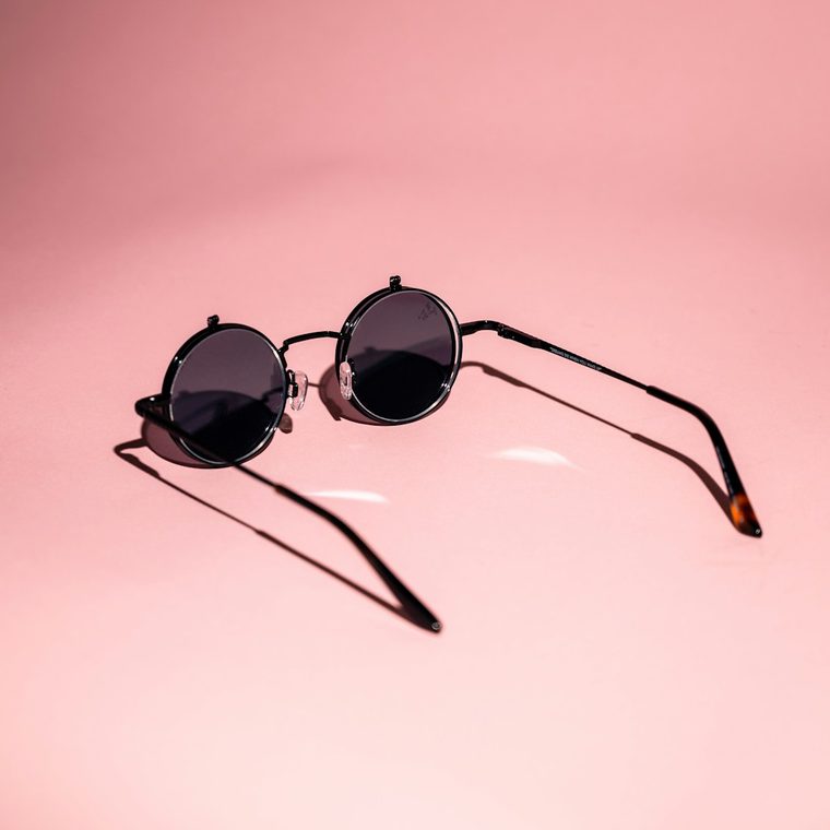 Gafas de sol redondas de metal sobre fondo rosa